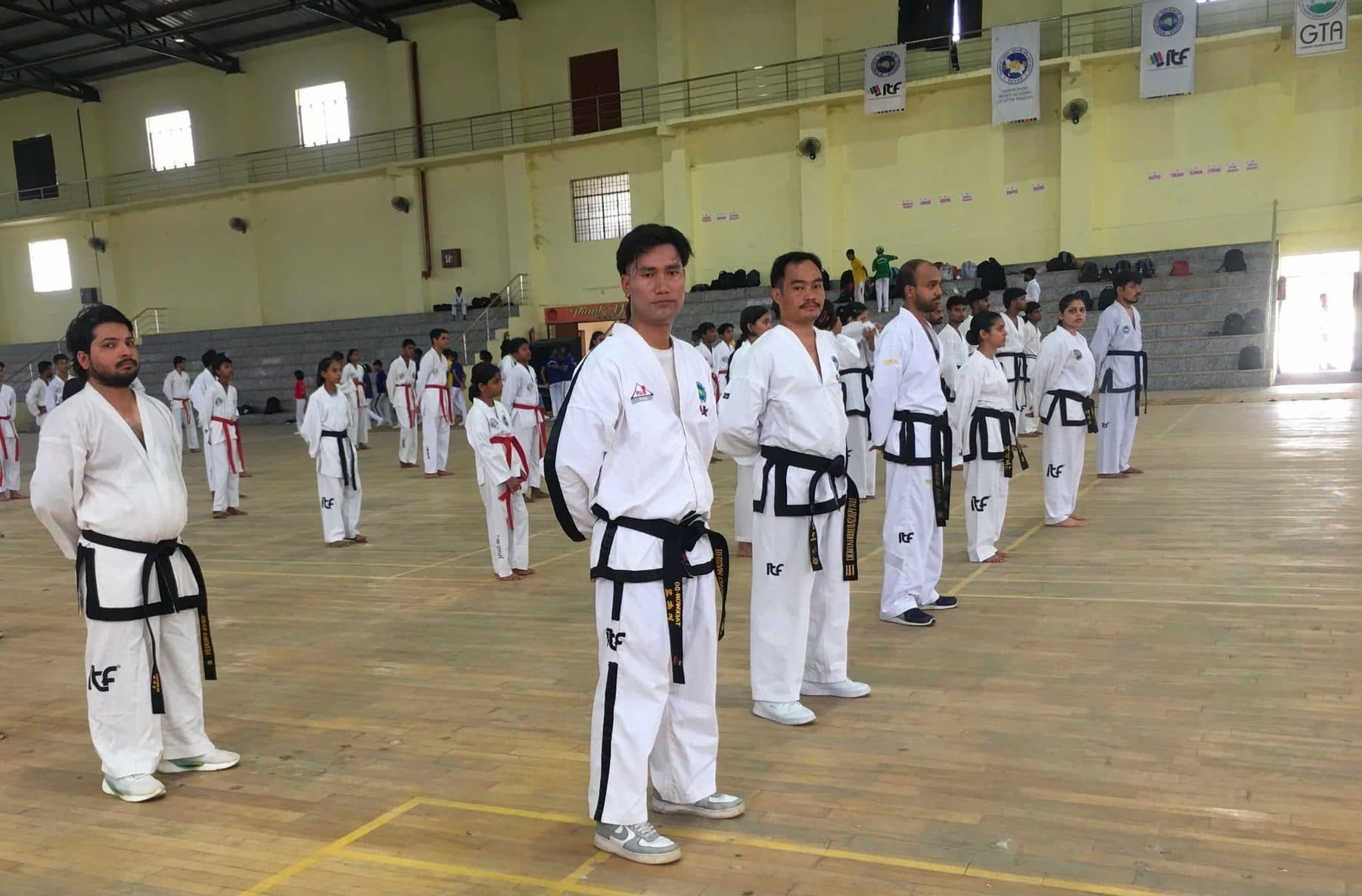 Black belts lined up for training in the sports college hall